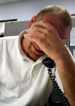 Man on the phone who is holding his head in his hand and stressed